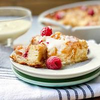 Closeup view of a serving of Croissant Bread Pudding with fresh raspberries.