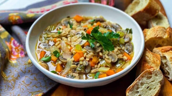 Bowl of Mushroom Barley Soup with fresh parsley and French bread