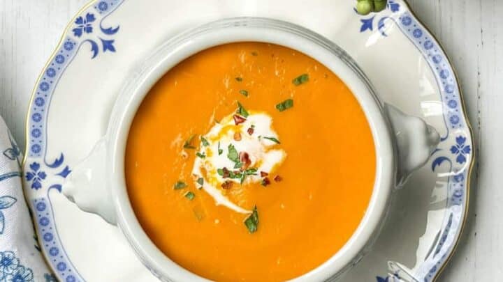 Top view of Carrot Soup with blue and white plate and spring greens
