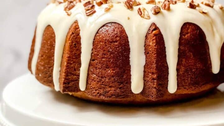 Side view of unsliced Hummingbird Cake with Cream Cheese Frosting and pecan sprinkles