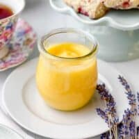 Lemon curd in a glass jar with tea