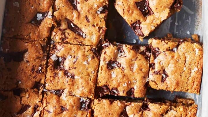 A pan of chocolate chip blondies cut into squares, with one piece separated and slightly raised above the others—perfect for a sweet finish to your May Healthy Dinners.