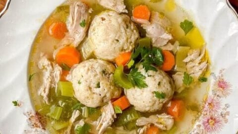 Vertical top view of a bowl of Matzo Ball Soup with Chicken and fresh herbs
