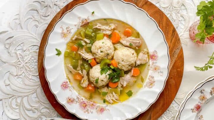 Top view of a bowl of Matzo Ball Soup with Chicken, vegetables, and herbs
