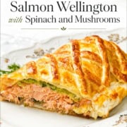 A slice of salmon Wellington with spinach and mushrooms wrapped in golden pastry, served on a decorative plate, makes this classic salmon wellington an elegant and delicious centerpiece.