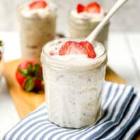 Closeup view of Strawberry Overnight Oats with a white spoon in a glass jar