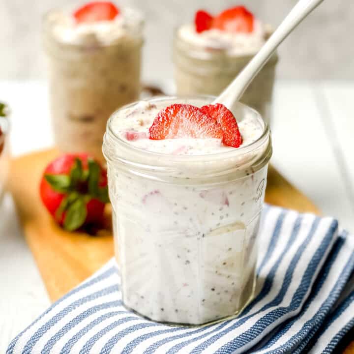Closeup view of Strawberry Overnight Oats with a white spoon in a glass jar