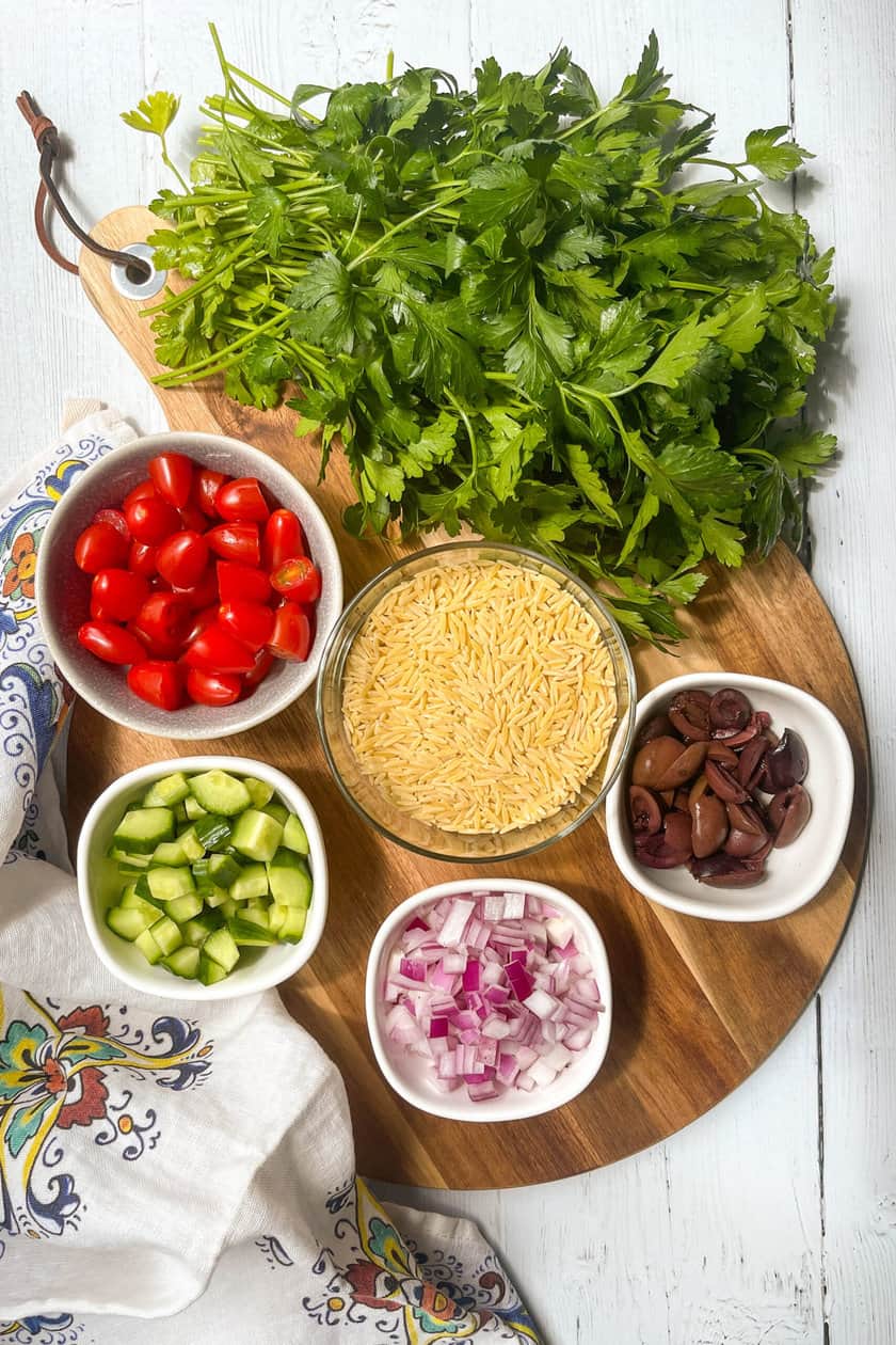 Top view of Greek Orzo Salad ingredients on a round wood board