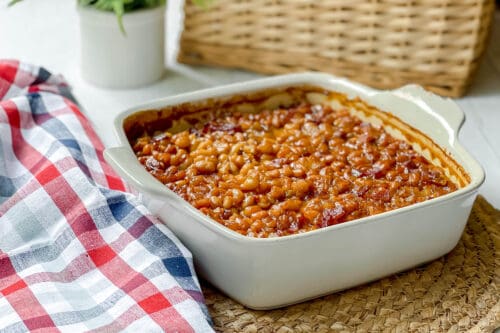 Side view of Boston Baked Beans in casserole dish on a woven mat