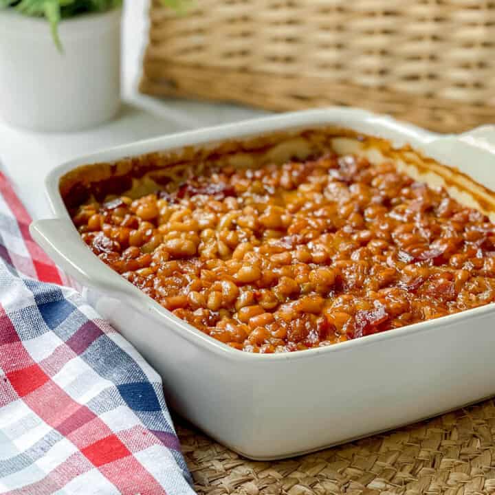 Side view of Boston Baked Beans in casserole dish on a woven mat
