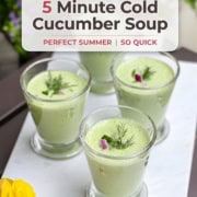 Four glasses of refreshing cucumber soup garnished with dill and red onion sit on a white tray, with yellow flowers in the foreground and promotional text above.