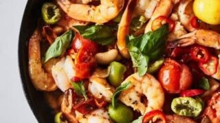 A skillet filled with cooked shrimp, cherry tomatoes, sliced green and red peppers, and fresh basil makes for one of the ultimate One Pot Summer Dinners, served alongside pieces of crusty bread.