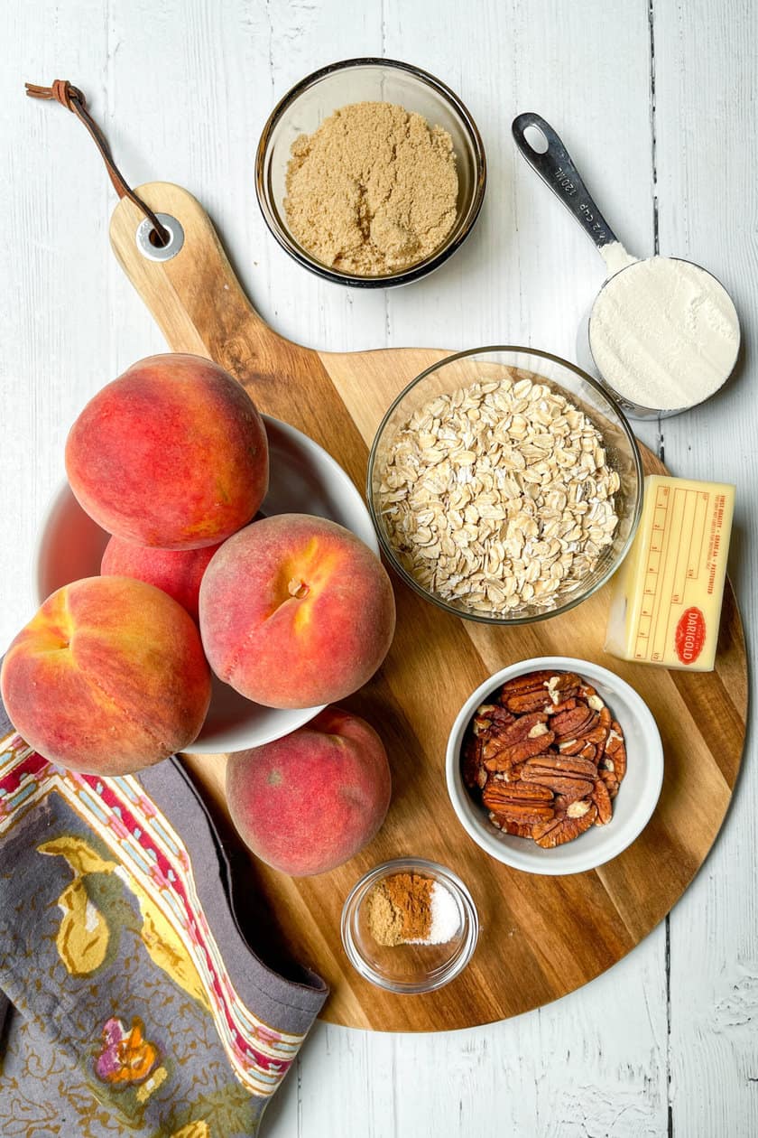 Top view of peach crisp ingredients on a round wood board