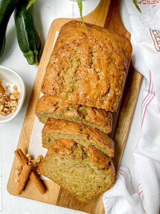 Top view of sliced Zucchini Bread loaf with fresh zucchini in the background