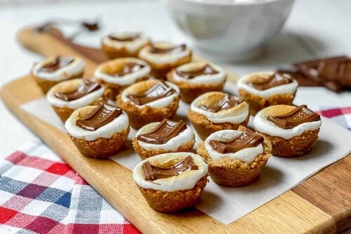 S'mores Cookie Cups on a wood board with a gingham checkered linen
