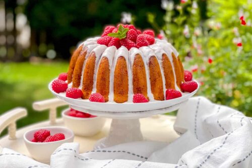 White Chocolate Raspberry Bundt Cake on a stand for afternoon tea in the garden
