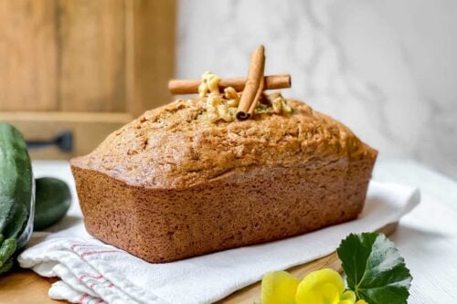 Side view of Zucchini Bread loaf with cinnamon sticks and walnuts
