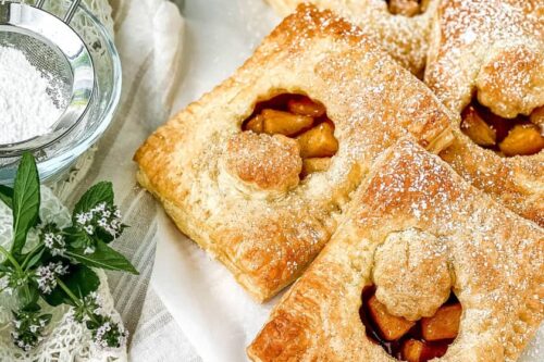 Top view of French Apple Pie Tarts with fresh flowers and powdered sugar