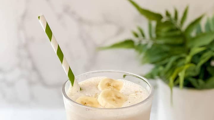 Side view of Oatmeal Smoothie with slices of bananas and a green and white straw
