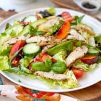 Side view of Stone Fruit Chicken Salad on a round wood cutting board