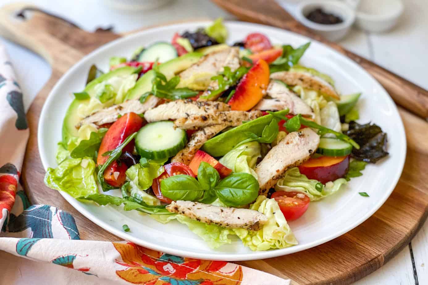 Side view of Stone Fruit Chicken Salad on a round wood cutting board