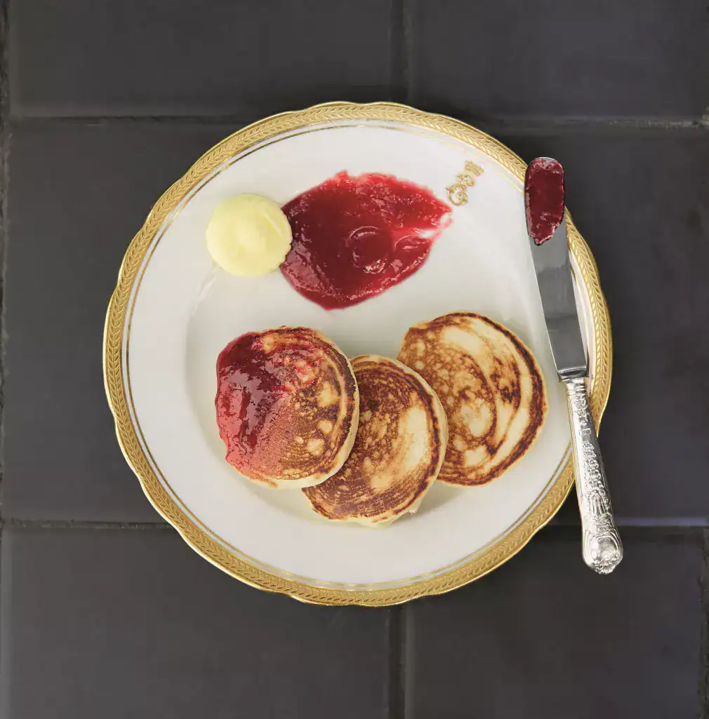 Three Queen Elizabeth's Drop Scones on a plate with clotted cream and jam.