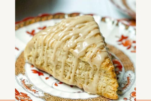 Apple cinnamon scone with maple glaze on a fall plate and napkin, styled for autumn afternoon tea. Simple, cozy fall baking recipe for teatime or snacks