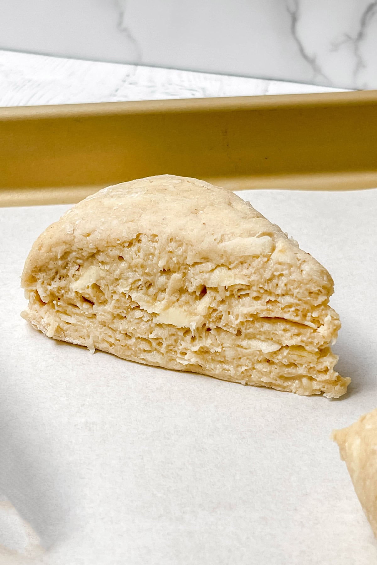 Unbaked apple cinnamon scone on a parchment lined sheet pan ready for baking.