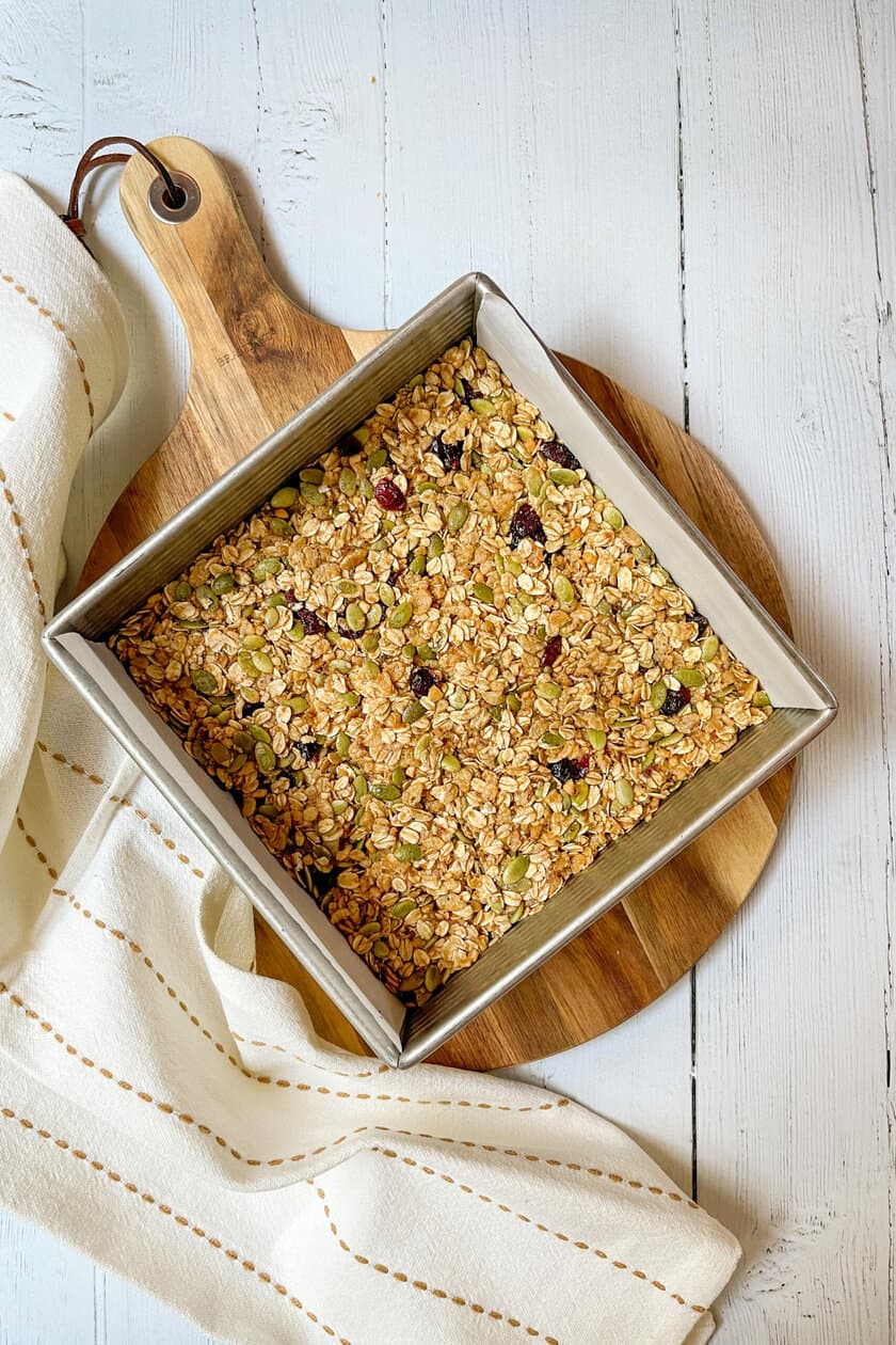 Top view of pressed Chewy Granola mixture in a square baking pan ready for chilling.