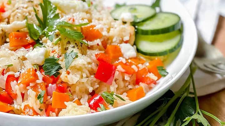 Closeup view of Instant Pot Greek Chicken and Rice in a white bowl with feta