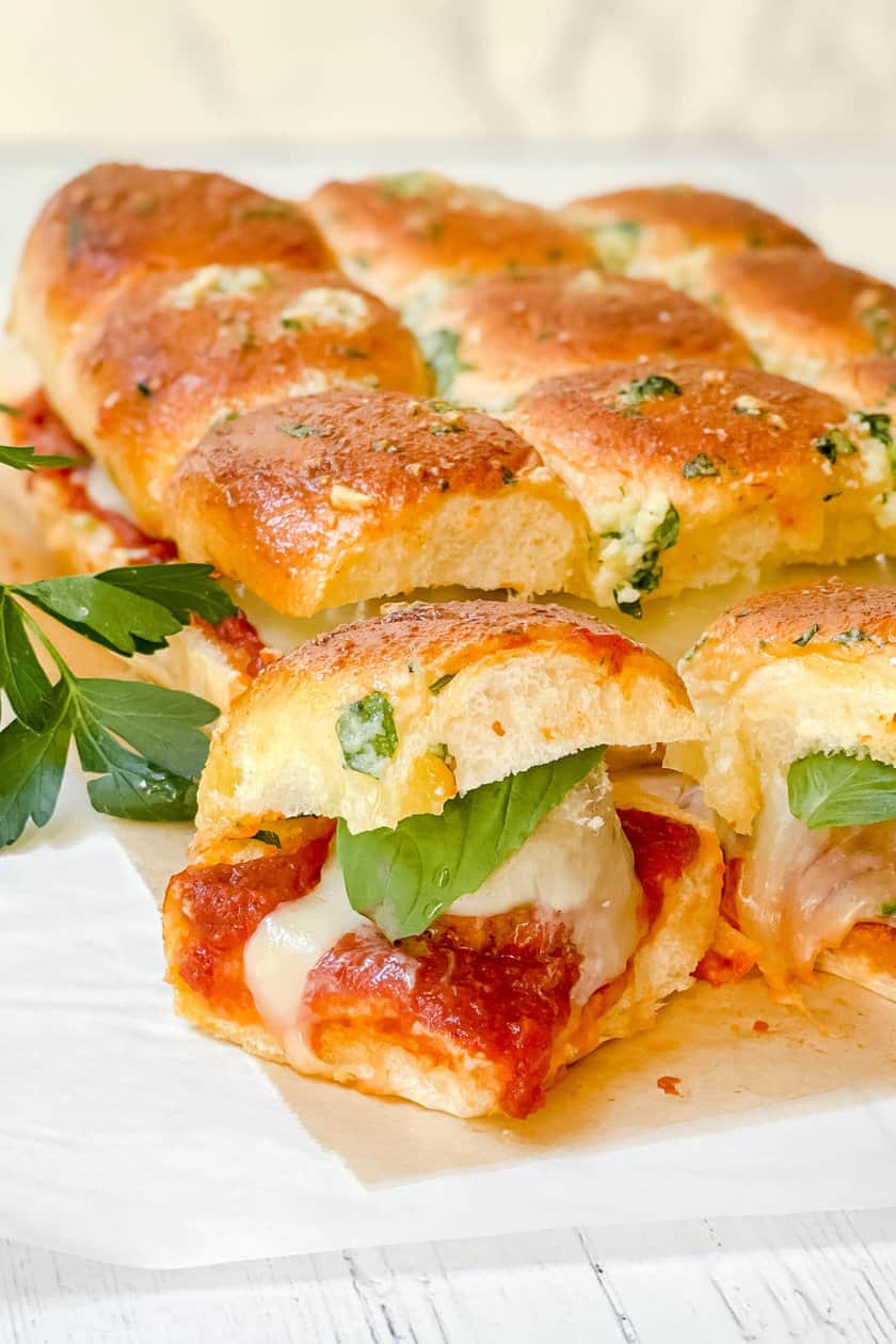 Closeup view of Meatball Hawaiian Roll Sliders with fresh basil and mozzarella cheese