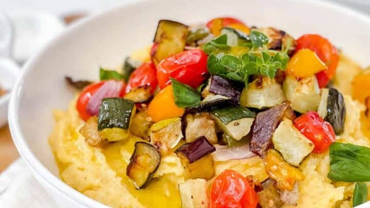 Side view of Sheet Pan Ratatouille served over creamy polenta with fresh herbs