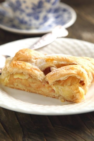 Closeup view of sliced apple strudel on a white plate with tea.