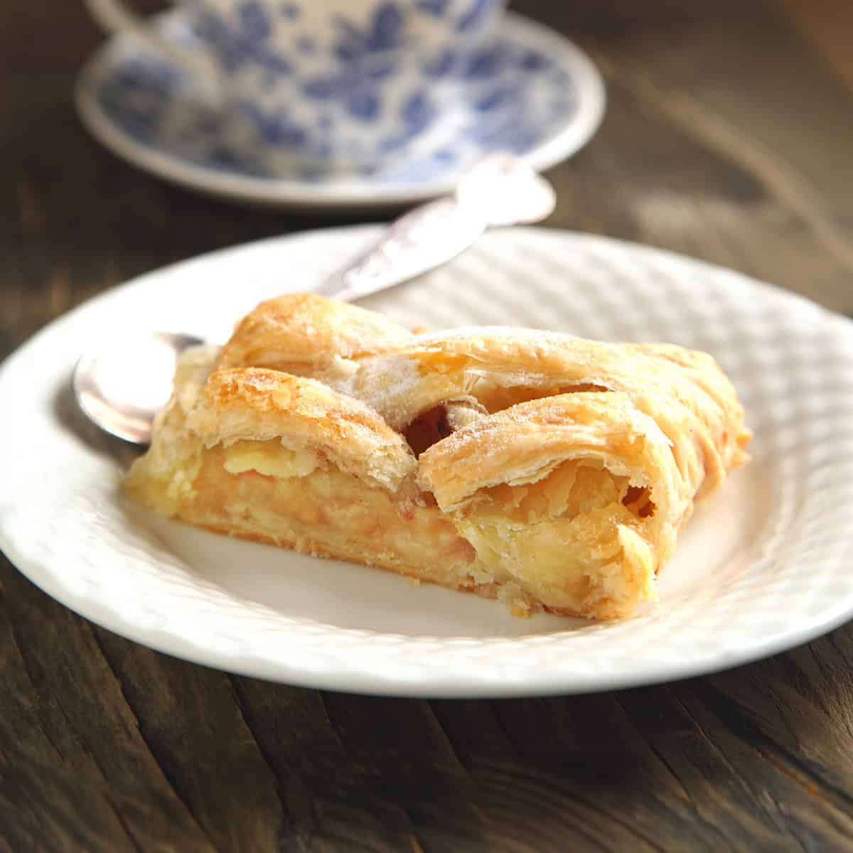 Closeup view of sliced apple strudel on a white plate with tea.