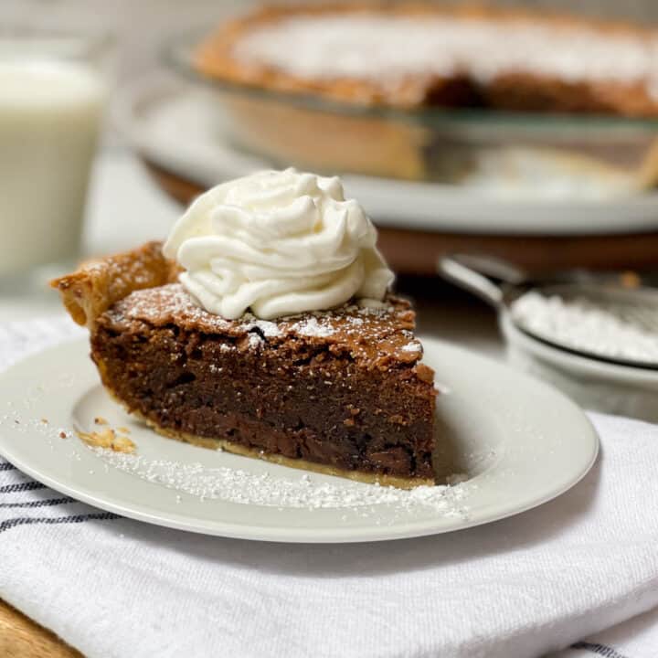 Side view of sliced Brownie Pie with whipped cream on a white plate
