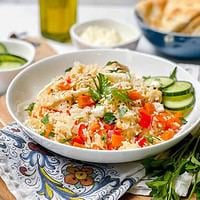 Side view of Instant Pot Greek Chicken in a white bowl with cucumber slices and feta