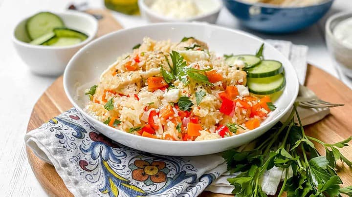 Side view of Instant Pot Greek Chicken in a white bowl with cucumber slices and feta