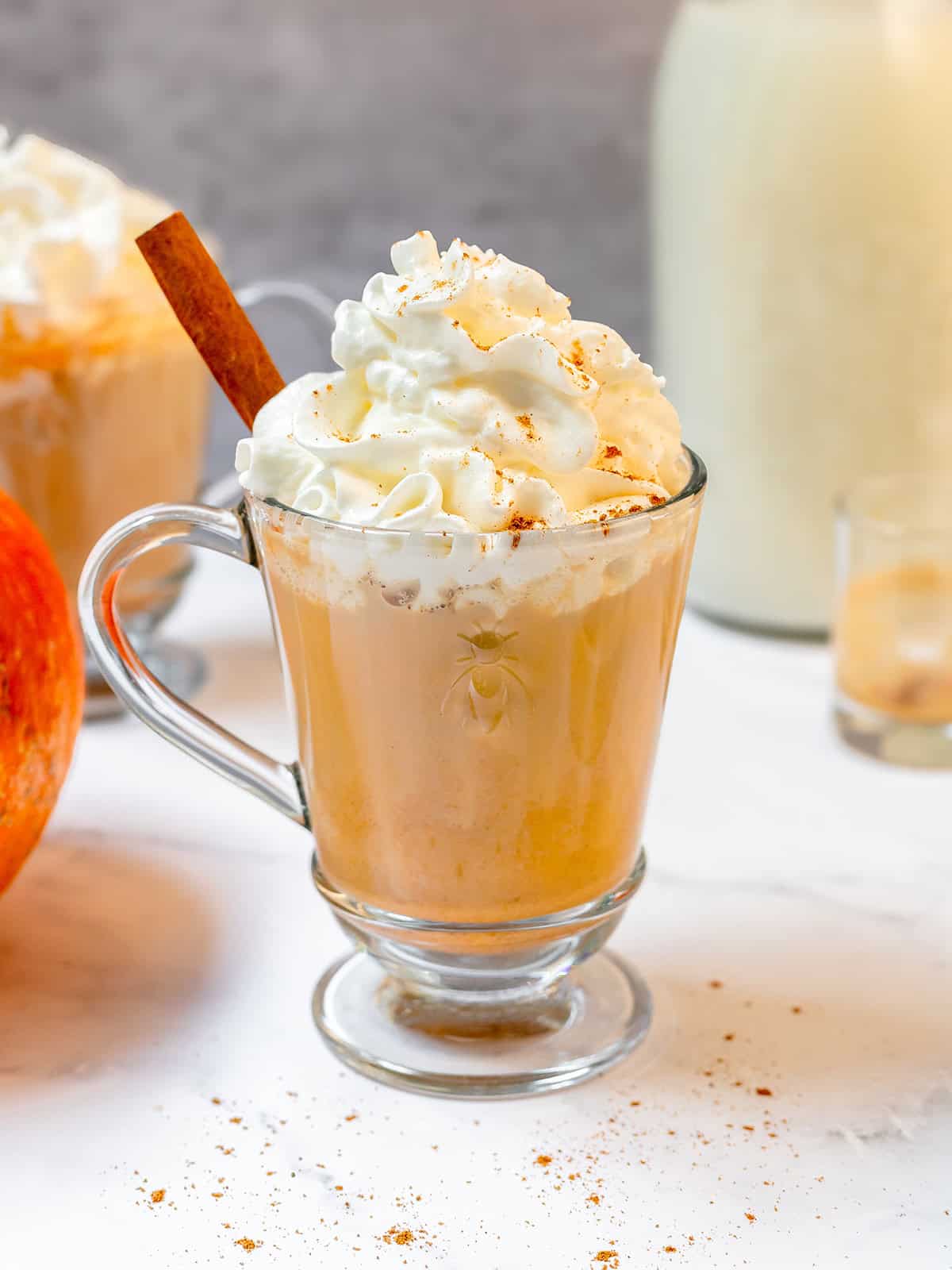Closeup Pumpkin Spice Latte topped with whipped cream and pumpkin pie spice in a glass mug.