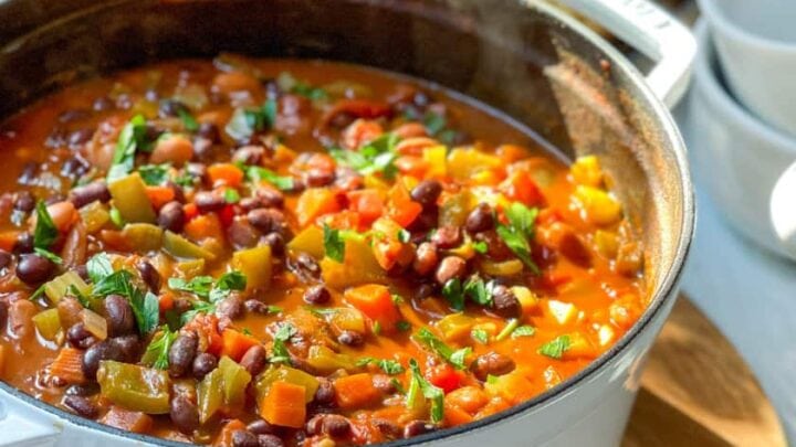 Side view of Vegetarian Chili in Staub Dutch Oven with Cast Iron Cornbread in the background