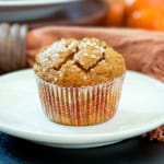 Square image of healthy pumpkin muffin in a fall paper sleeve resting on a small plate.