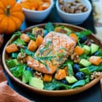 Grilled Salmon fillet on a bed of harvesst greens including roasted butternut squash, avocado and fresh blueberries.