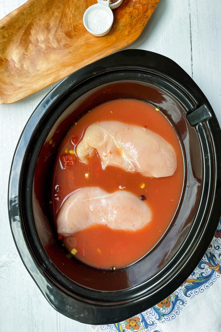 Top view of Slow Cooker Chicken and Rice Burrito Bowl ingredients with 2 uncooked chicken breasts