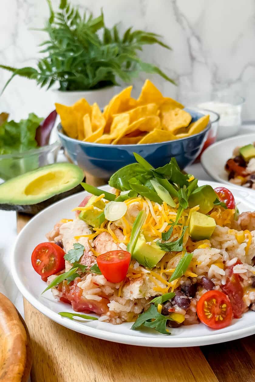 Top side view of Slow Cooker Chicken and Rice Burrito Bowl with toppings, chips and salsa
