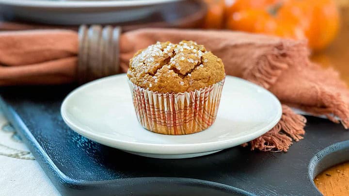 Closeup view of Pumpkin Muffins with no refined sugar on a white plate with pumpkins in the background