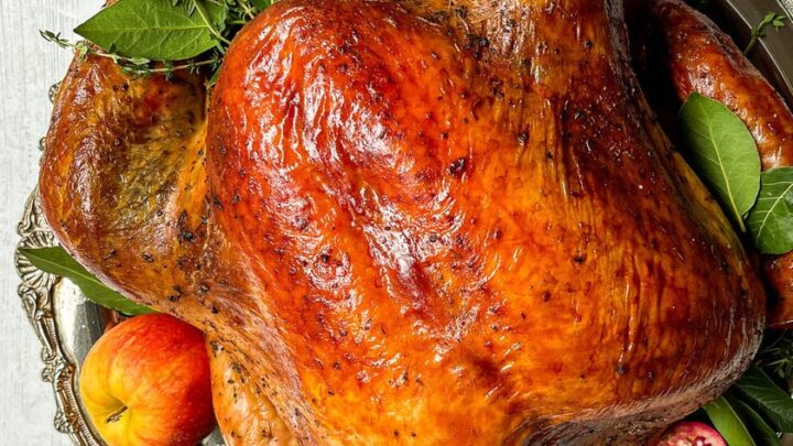 Top view of Herb Roasted Turkey on a silver platter with apples, pomegranates and fresh herbs
