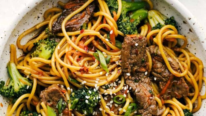 A bowl of beef lo mein with noodles, broccoli, sliced beef, and sesame seeds, garnished with green onions—perfect for November 20 Minute Dinners.