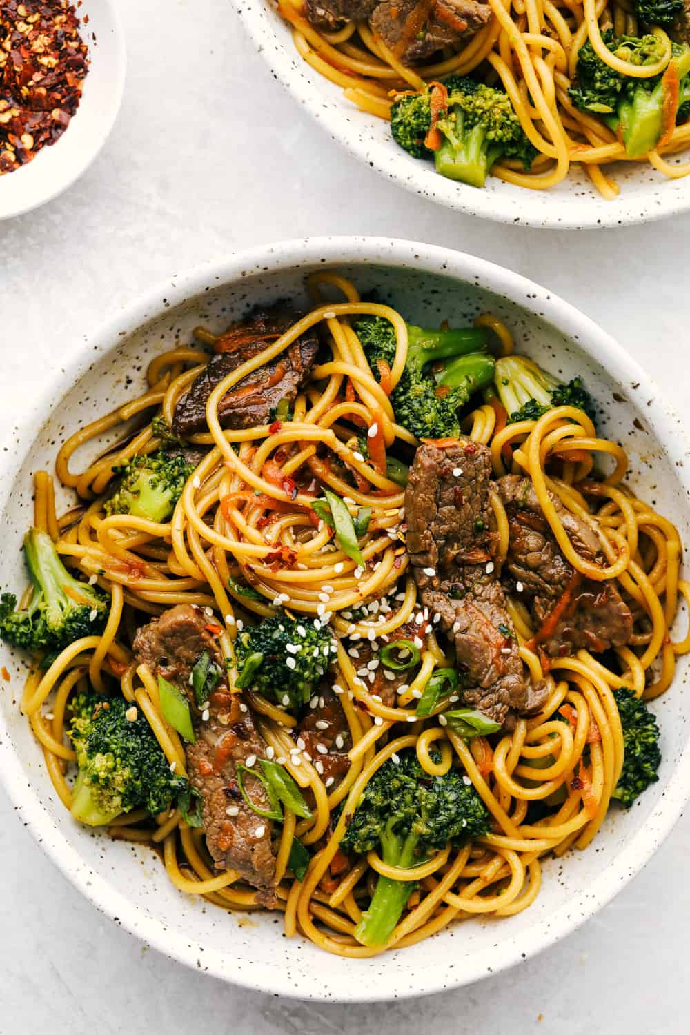 A bowl of beef lo mein with noodles, broccoli, sliced beef, and sesame seeds, garnished with green onions-perfect for November 20 Minute Dinners.