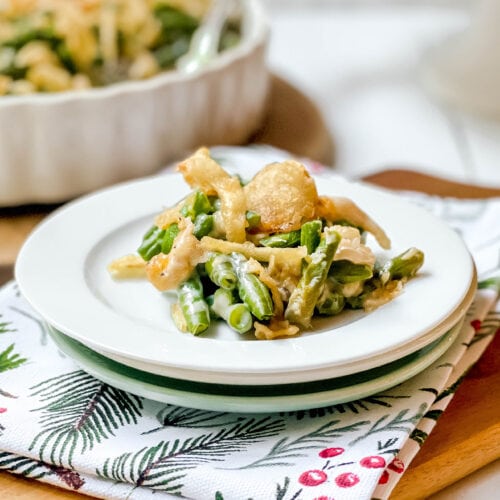 Serving of Green Bean Casserole on a white plate with casserole in the background