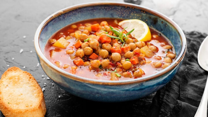 Side view of Moroccan Bean Soup in a blue bowl with a lemon slice