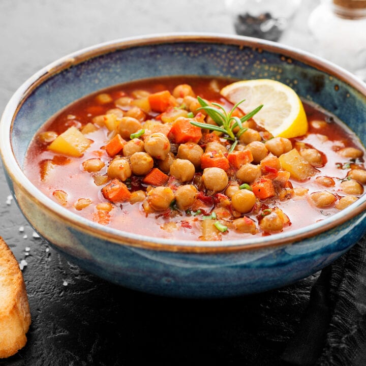 Side view of Moroccan Bean Soup in a blue bowl with a lemon slice